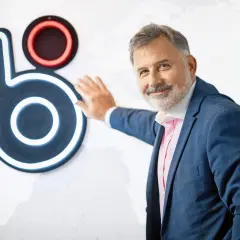 Mężczyzna w garniturze opiera się o logo BLIK. Czy to on wymyślił BLIK?