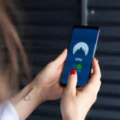 Dłoń trzyma smartfon z włączoną aplikacją VPN, gotową do zabezpieczenia połączenia, jak w najnowszych wersjach android 15.