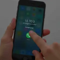 Palec dotyka ikony połączenia alarmowego na ekranie telefonu, pokazując, jak odblokować telefon przez połączenie alarmowe.