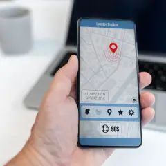 Dłoń trzyma smartfon z mapą i pinezką lokalizatora. To najlepsza darmowa aplikacja do śledzenia telefonu, z przyciskiem SOS.
