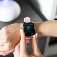 Różowy smartwatch na nadgarstku pokazuje ekran odtwarzania muzyki. Dowiedz się, jak sparować zegarek z telefonem, by cieszyć się ulubionymi utworami.