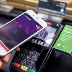 Kupujący zbliża telefon do terminala płatniczego, pokazując ekran z potwierdzeniem płatności. Tak łatwo można płacić telefonem.
