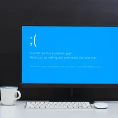 Smutna buźka na niebieskim ekranie komputera. "Your PC ran into a problem again." - klasyczny bluescreen.