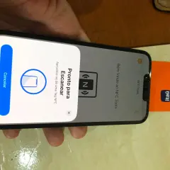 iPhone gotowy do skanowania tagu NFC. Obok telefonu leży pomarańczowa karta z logo banku.