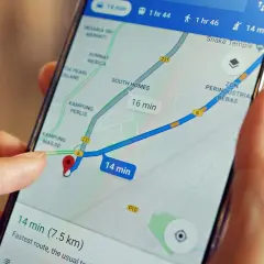 Palec dotyka ekranu telefonu z mapą, pokazując trasę i czas dojazdu. Dowiedz się, jak wysłać pinezkę z lokalizacją.