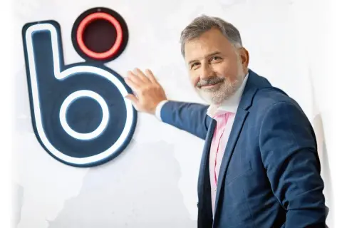 Mężczyzna w garniturze opiera się o logo BLIK. Czy to on wymyślił BLIK?