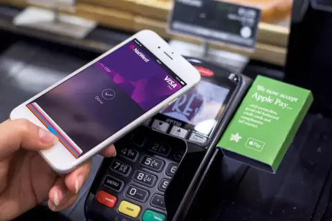 Kupujący zbliża telefon do terminala płatniczego, pokazując ekran z potwierdzeniem płatności. Tak łatwo można płacić telefonem.
