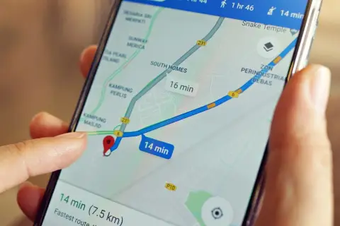 Palec dotyka ekranu telefonu z mapą, pokazując trasę i czas dojazdu. Dowiedz się, jak wysłać pinezkę z lokalizacją.