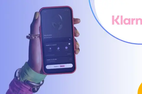 Dłoń trzyma telefon z aplikacją Klarna, pokazującą opcje płatności za słuchawki w ratach lub za 30 dni. Klarna co to? To wygodny sposób na zakupy.