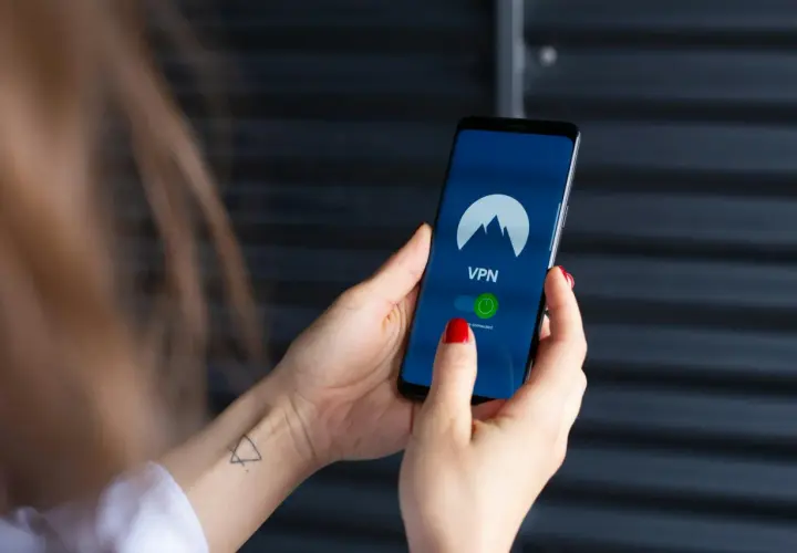 Dłoń trzyma smartfon z włączoną aplikacją VPN, gotową do zabezpieczenia połączenia, jak w najnowszych wersjach android 15.