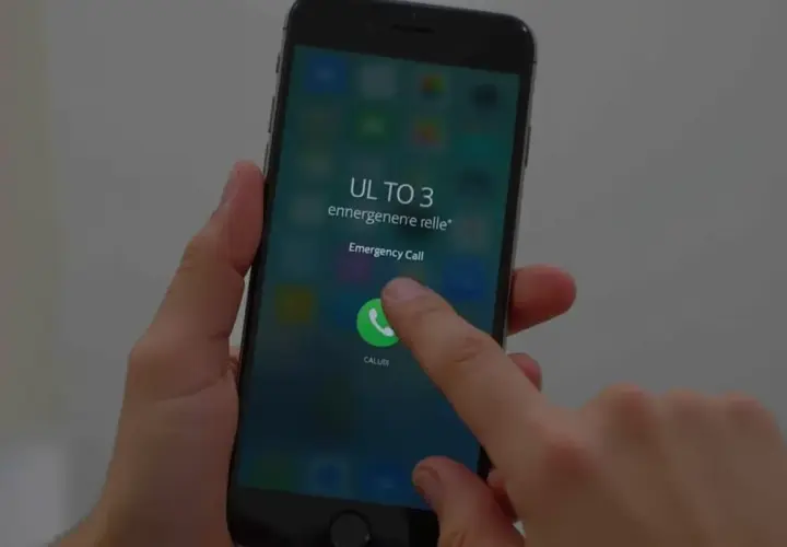 Palec dotyka ikony połączenia alarmowego na ekranie telefonu, pokazując, jak odblokować telefon przez połączenie alarmowe.