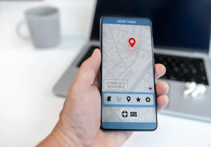 Dłoń trzyma smartfon z mapą i pinezką lokalizatora. To najlepsza darmowa aplikacja do śledzenia telefonu, z przyciskiem SOS.