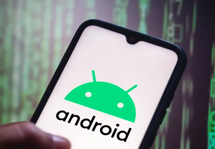 Dłoń trzyma smartfon z logo Android 10. Tło to zielony, rozmyty kod.