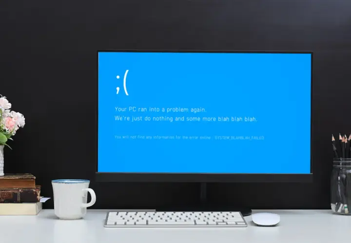 Smutna buźka na niebieskim ekranie komputera. "Your PC ran into a problem again." - klasyczny bluescreen.