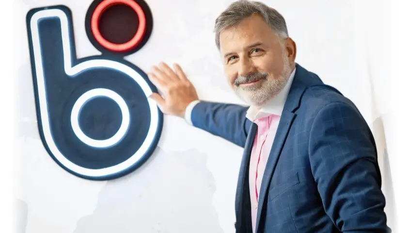 Mężczyzna w garniturze opiera się o logo BLIK. Czy to on wymyślił BLIK?