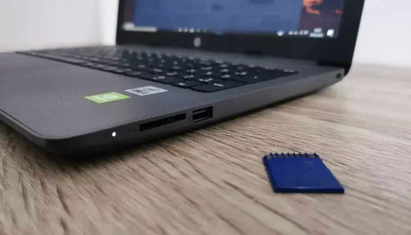Obok laptopa leży niebieska karta pamięci. Dysk jest zabezpieczony przed zapisem, co uniemożliwia modyfikację danych.