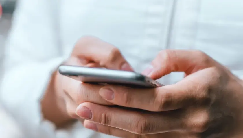 Dłonie trzymające smartfon, uważaj na oszustwa typu smishing, które mogą przyjść w każdej chwili.