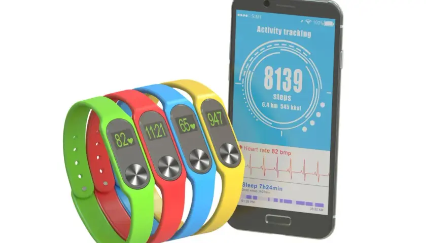 Kolorowe opaski monitorujące aktywność i smartfon z aplikacją do liczenia kroków.