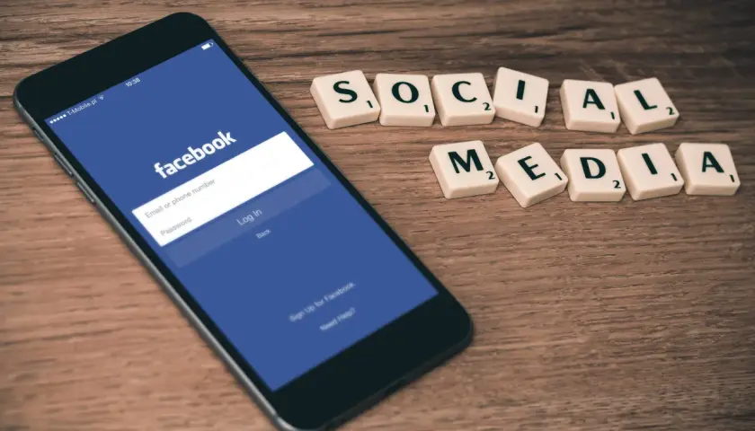 Telefon z ekranem logowania Facebooka i kafelki z napisem "SOCIAL MEDIA". Dowiedz się, jak zmienić email na FB.