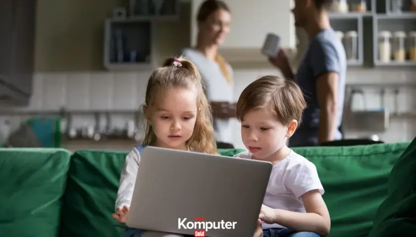 Dzieci korzystają z laptopa, rodzice czuwają. Kontrola rodzicielska na komputerze zapewnia bezpieczeństwo.
