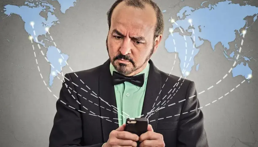 Mężczyzna zmartwiony patrzy na telefon, podczas gdy linie łączą go z mapą świata, sugerując globalny roaming, być może w Norwegii.