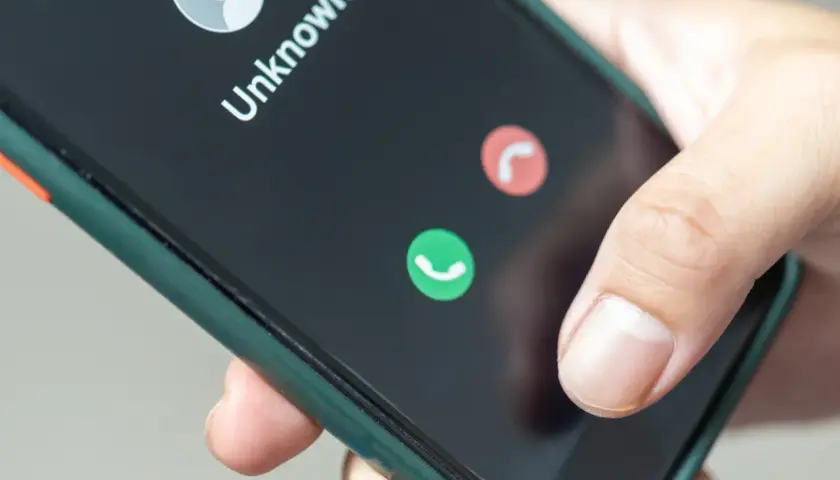 Dłoń trzyma smartfon z ekranem pokazującym nieznane połączenie. Zastanawiasz się, jak zastrzec numer jednorazowo?