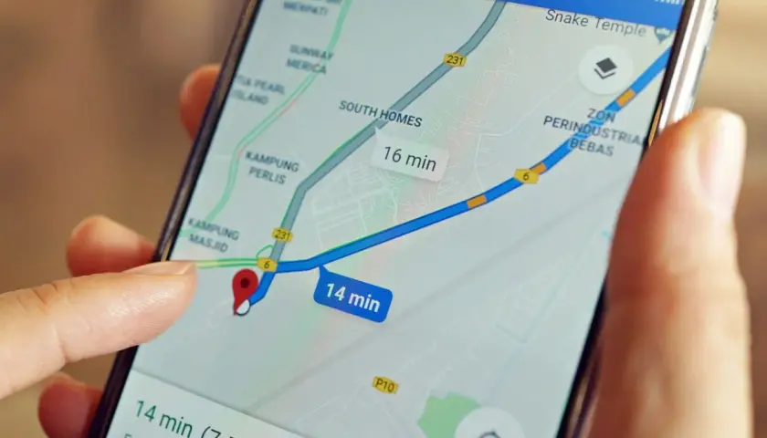 Palec dotyka ekranu telefonu z mapą, pokazując trasę i czas dojazdu. Dowiedz się, jak wysłać pinezkę z lokalizacją.