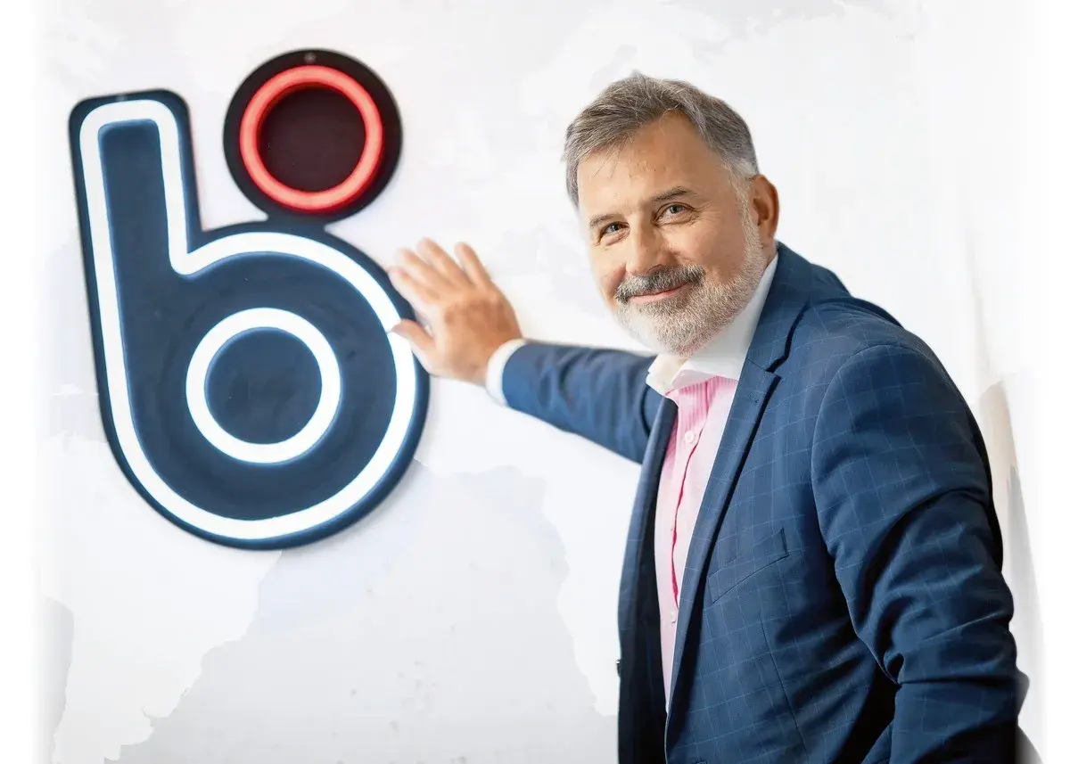 Mężczyzna w garniturze opiera się o logo BLIK. Czy to on wymyślił BLIK?