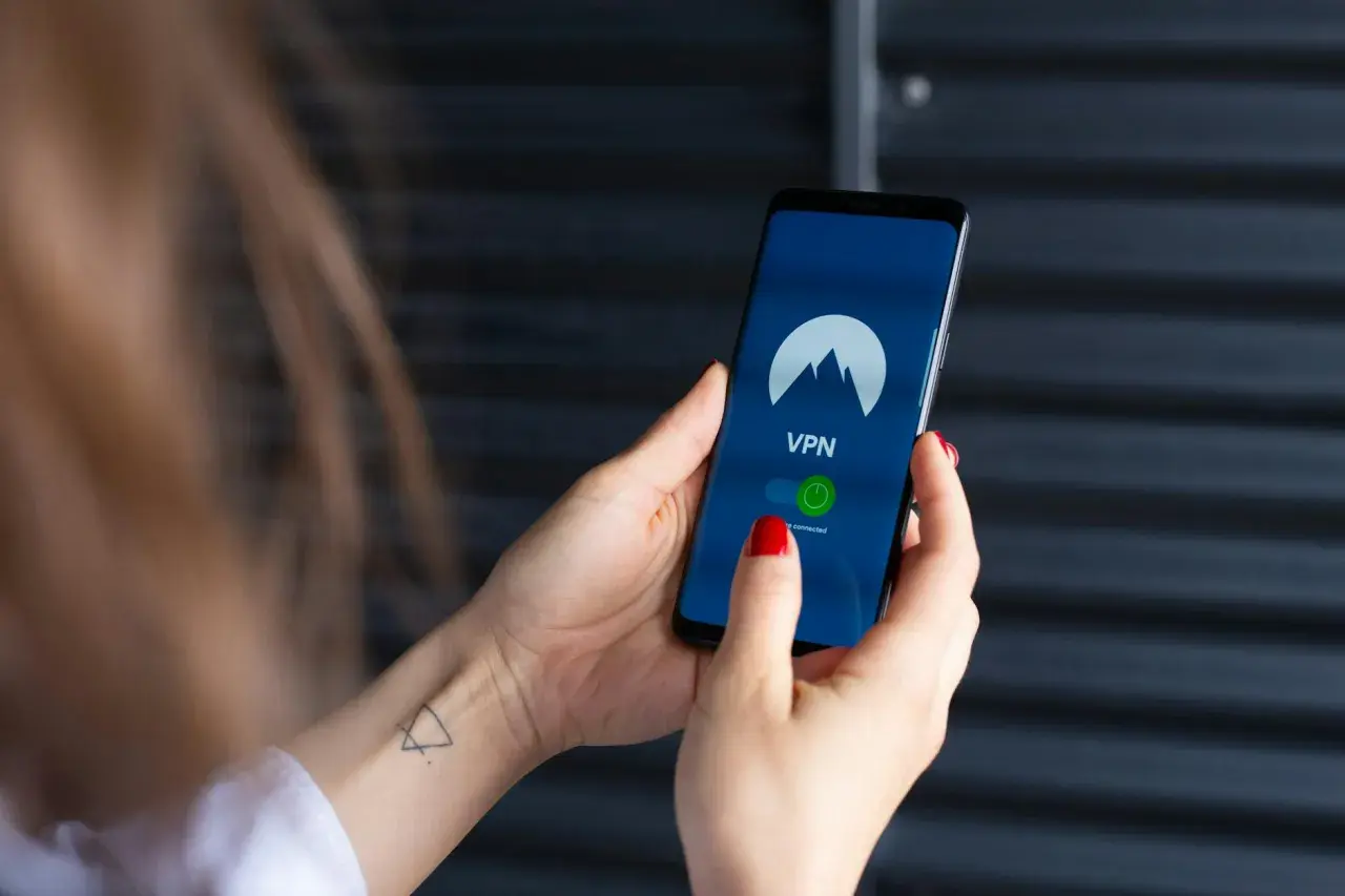 Dłoń trzyma smartfon z włączoną aplikacją VPN, gotową do zabezpieczenia połączenia, jak w najnowszych wersjach android 15.