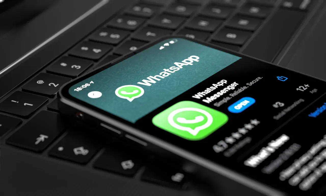 Telefon z aplikacją WhatsApp na klawiaturze laptopa. Wygodny sposób na korzystanie z WhatsApp na komputerze.