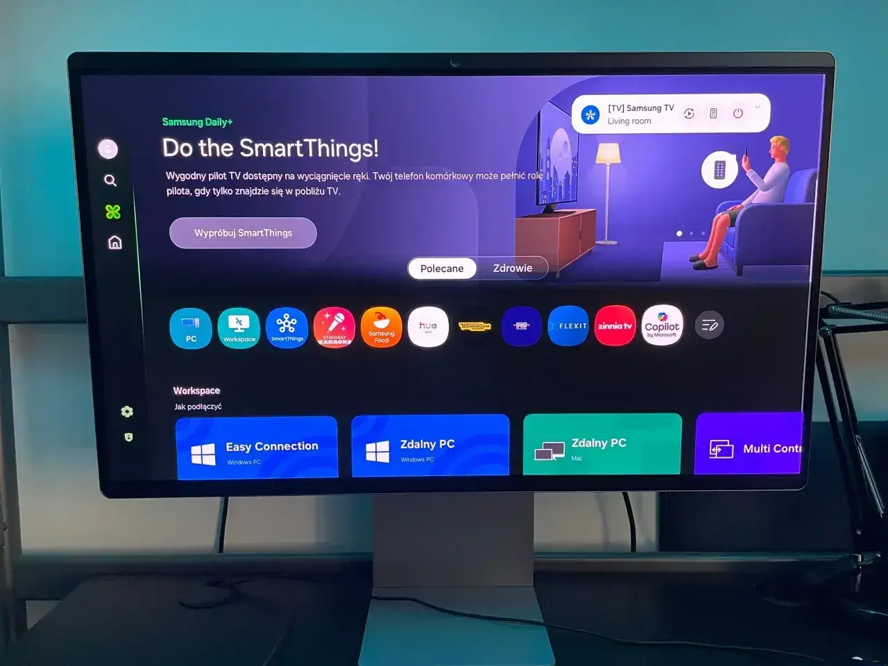 Ekran monitora z interfejsem Tizen, prezentujący aplikacje SmartThings, zdalny dostęp do PC i inne funkcje.