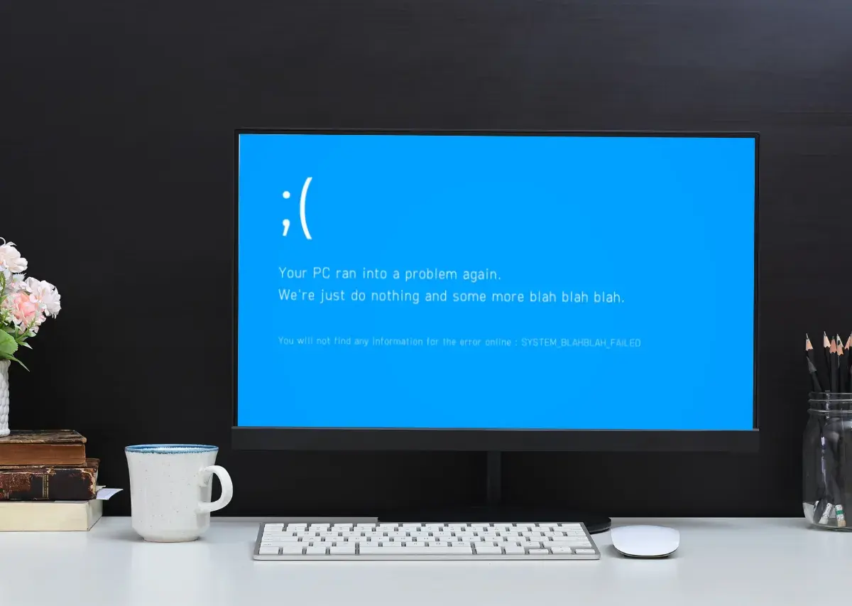 Smutna buźka na niebieskim ekranie komputera. "Your PC ran into a problem again." - klasyczny bluescreen.