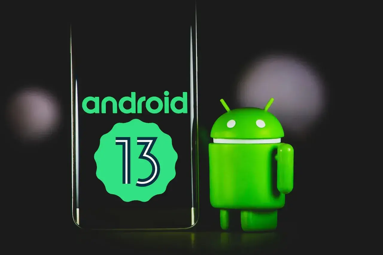 Zielony robot Android obok ekranu z napisem "android 13".