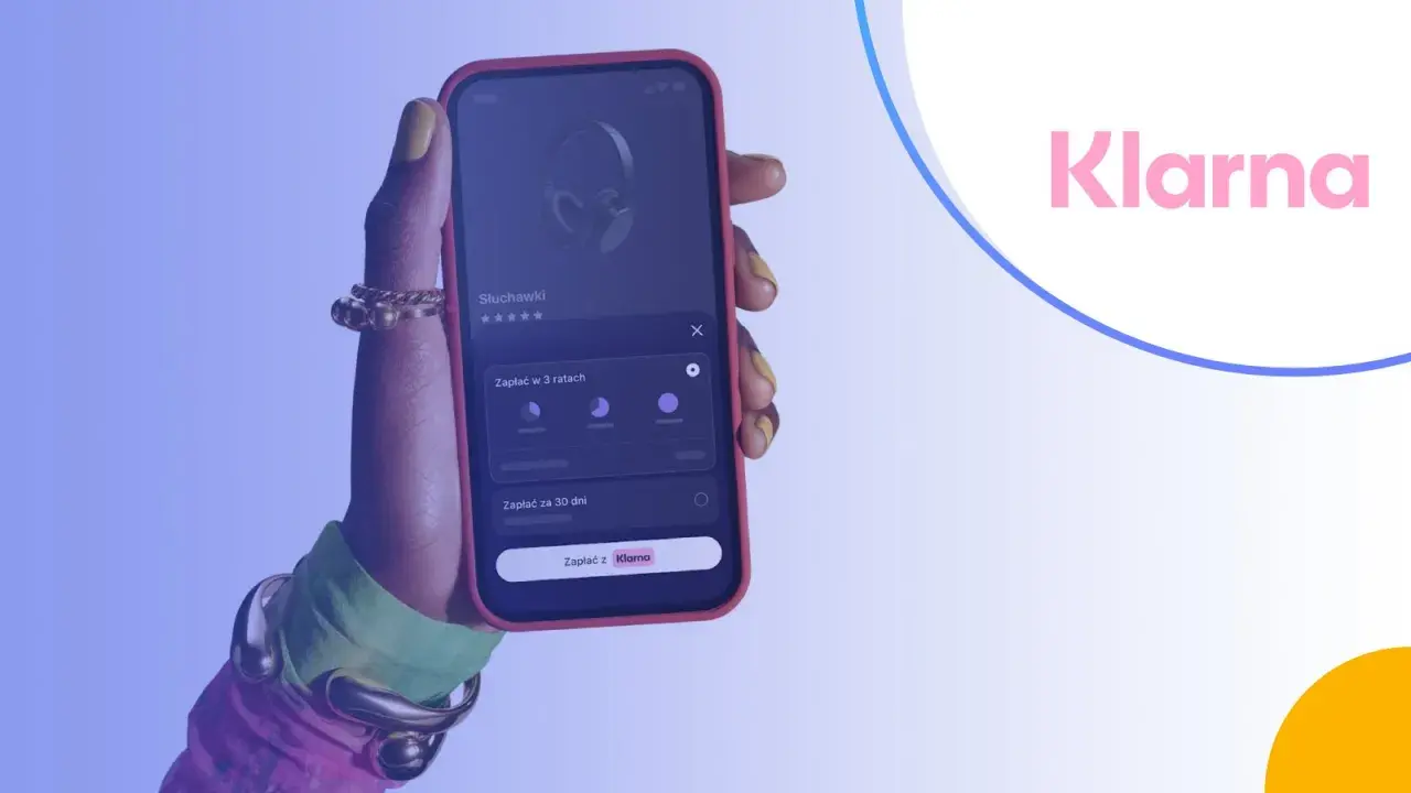 Dłoń trzyma telefon z aplikacją Klarna, pokazującą opcje płatności za słuchawki w ratach lub za 30 dni. Klarna co to? To wygodny sposób na zakupy.