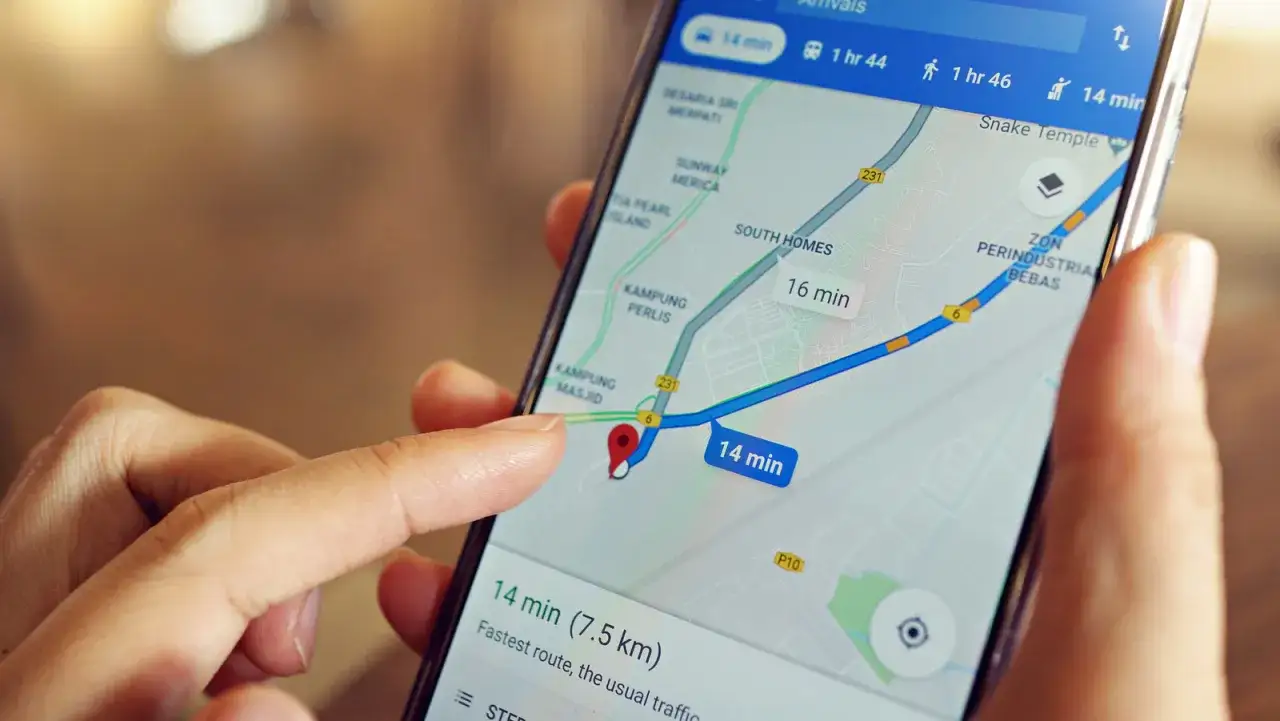 Palec wskazuje na mapę na ekranie telefonu, szukając odpowiedzi na pytanie: gdzie jest mój telefon? Nawigacja pokazuje trasę na 14 minut.