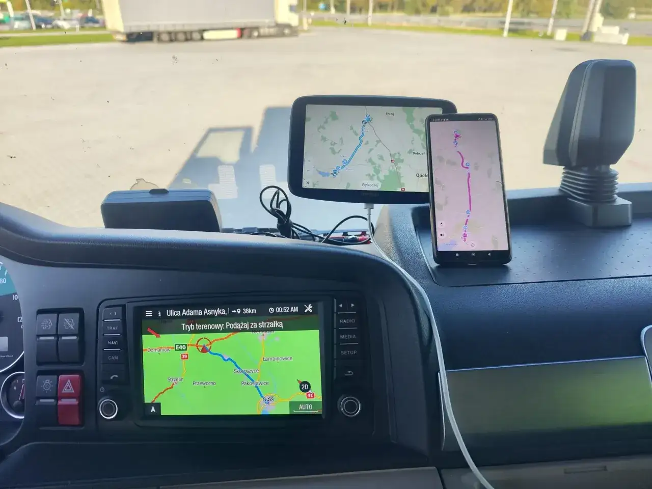 Dwie nawigacje samochodowe, jedna wbudowana, druga na telefonie, pokazują trasę. To darmowa nawigacja samochodowa, która ułatwia podróż.