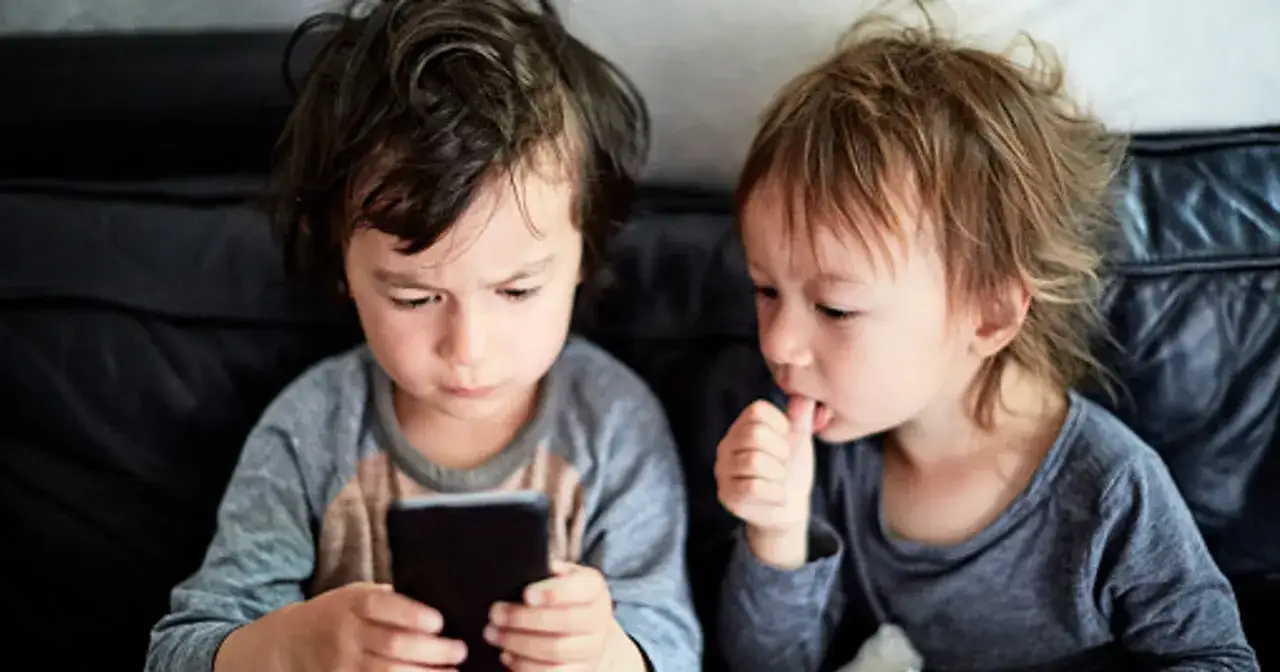 Dzieci oglądają bajkę na telefonie. Rodzice mogą użyć kontroli rodzicielskiej Android, by ograniczyć czas ekranowy.
