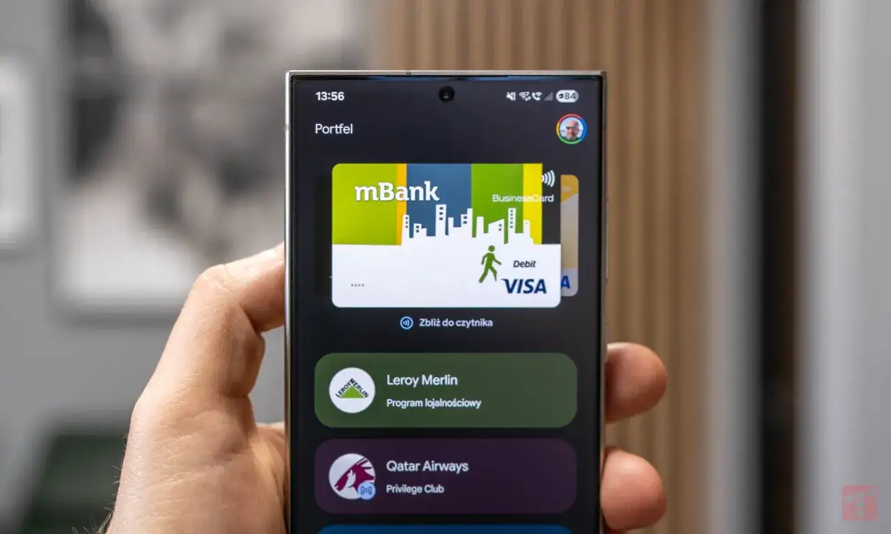 Telefon z aplikacją portfel, gdzie widać kartę mBank Visa. To pokazuje, jak działa płatność zbliżeniowa, podobnie jak w przypadku PayPal, co to jest i jak z niego korzystać.